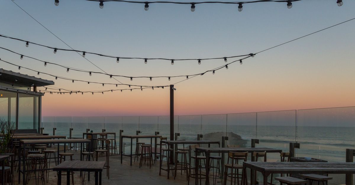 Terraza de madera con vista al mar y sillas junto a una casa costera